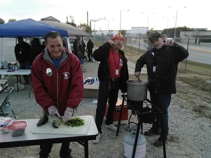 A volunteer chopping greens at an outdoor cookout while others look on