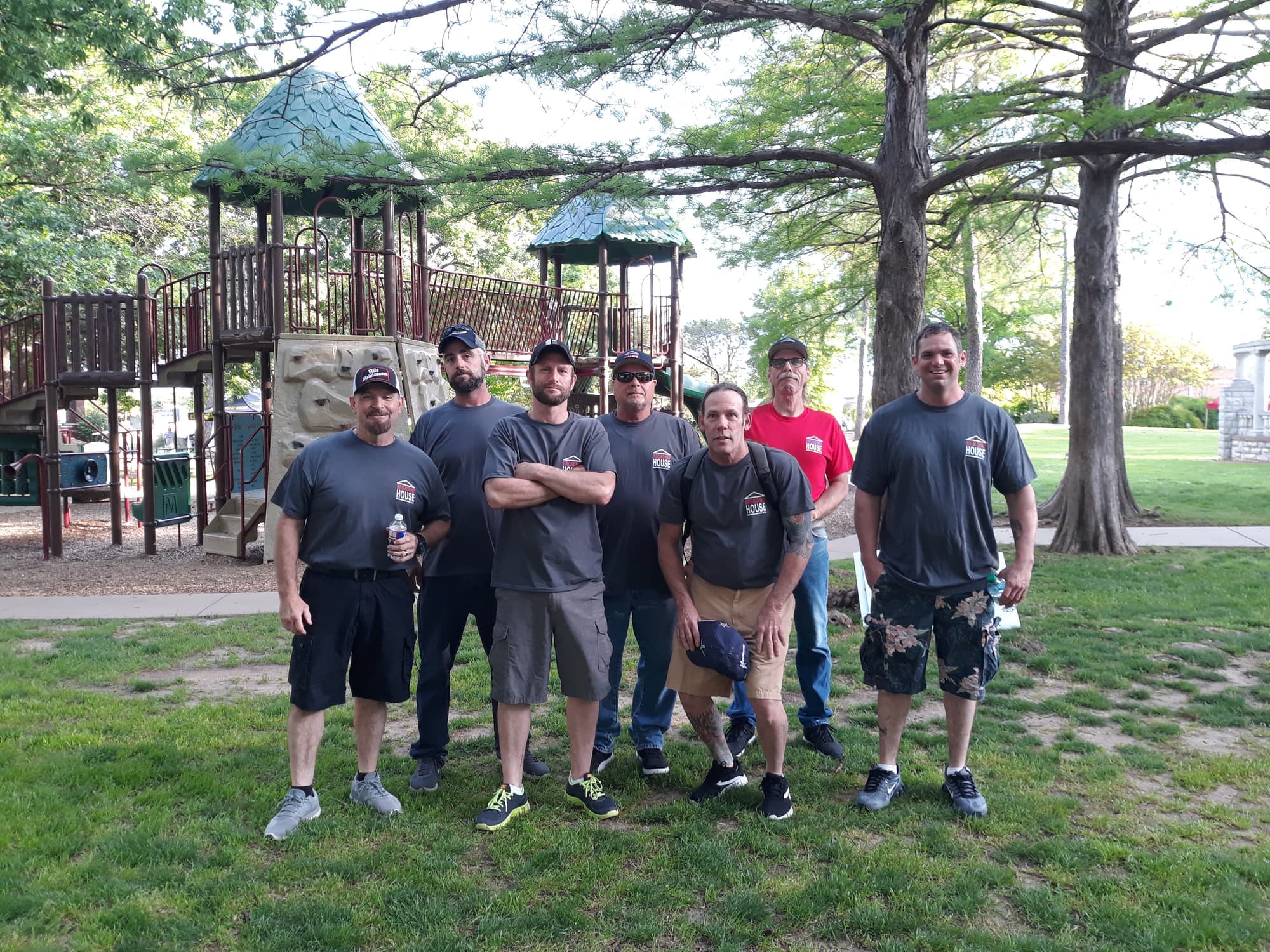 Broadway House volunteers in matching gray shirts standing together at the park playground
