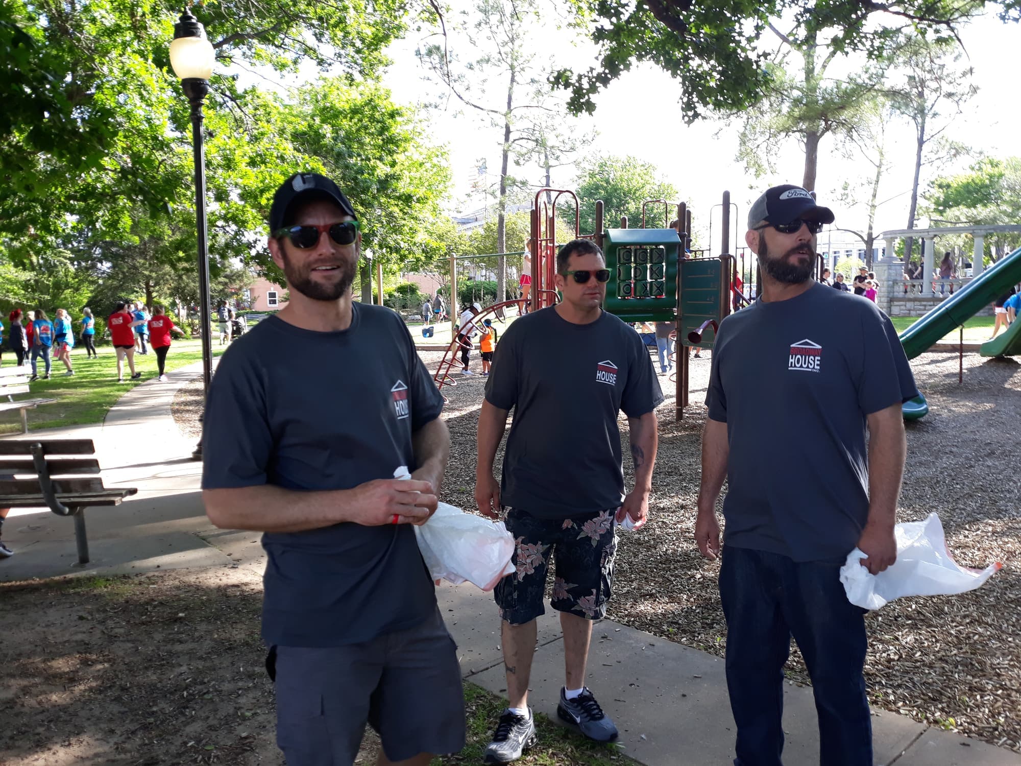 Three Broadway House volunteers carrying trash bags on the Heart Walk route