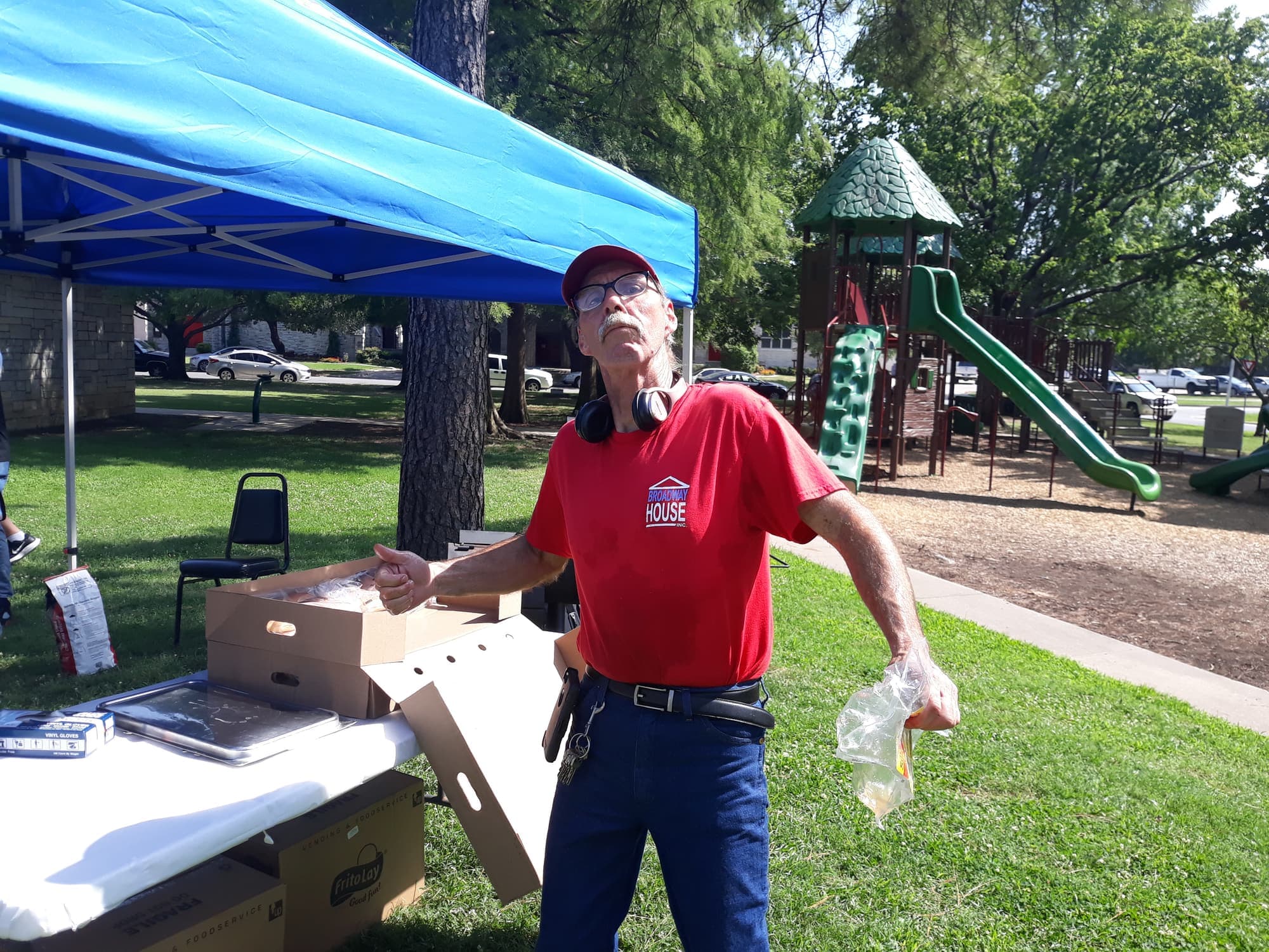 A volunteer in a red Broadway House shirt unloading boxes under the tent